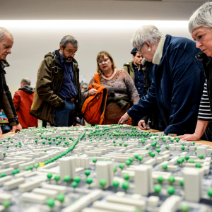 Eine Gruppe von Menschen betrachtet ein architektonisches Modell des Stadtteils.