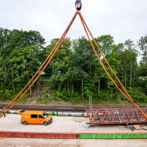 Mensch und Fahrzeug sehen neben den massiven Stahlträgern klein aus