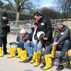 Eine Gruppe von Menschen zieht sich gelbe Gummistiefel an.