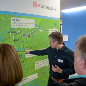Ein Mitarbeiter der HOCHBAHN deutet auf eine Stadtkarte mit geplantem Streckenverlauf der U5.