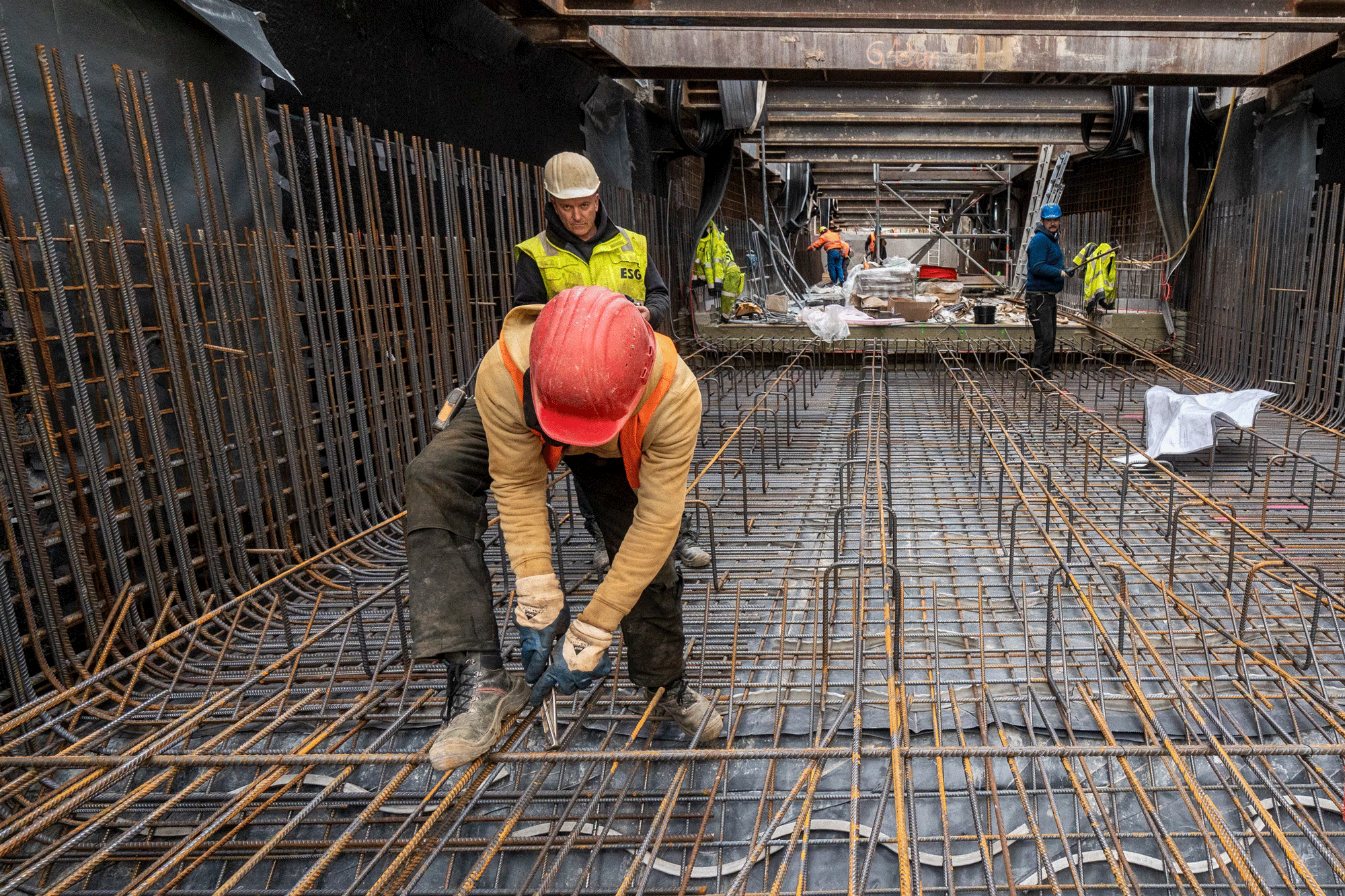 In der Baugrube: Arbeiter flechtet Bewehrung (Drahtstäbe)