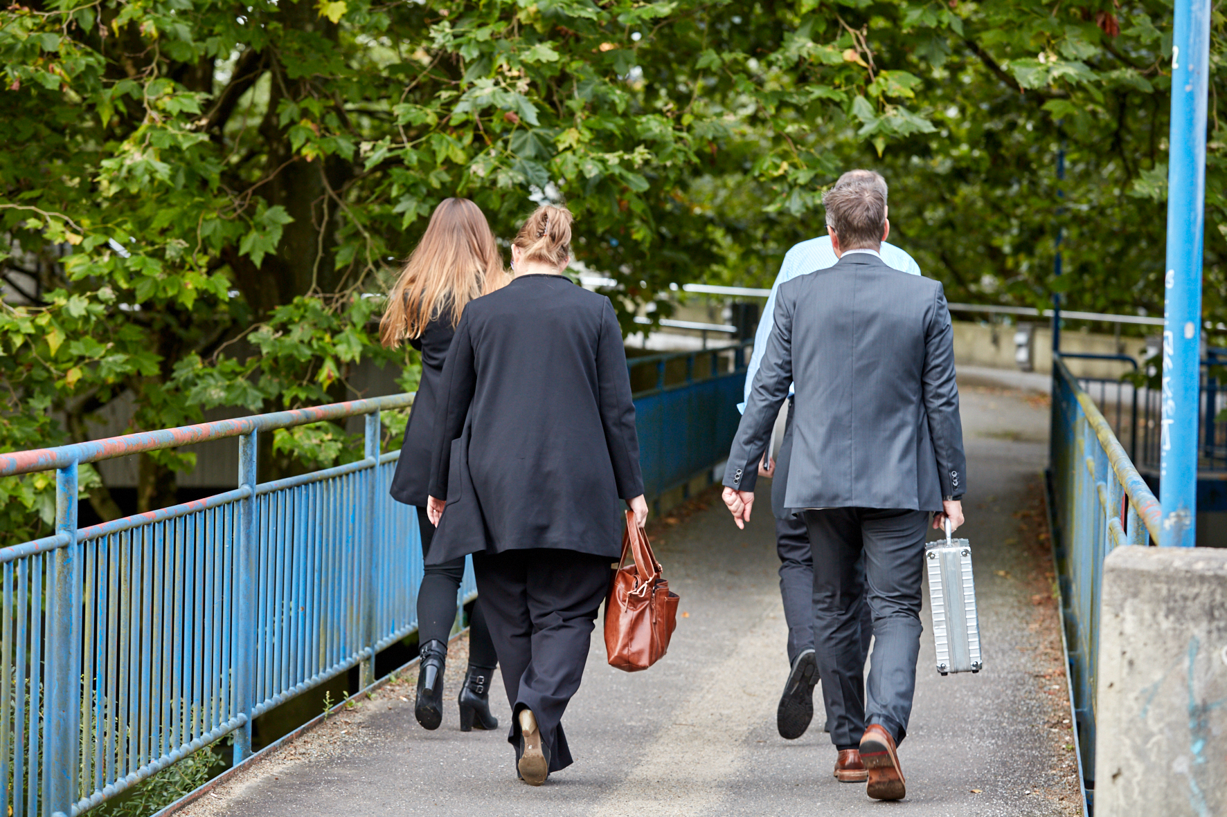 Vier Menschen von hinten: Sie laufen auf einer Fußgängerbrücke der City Nord