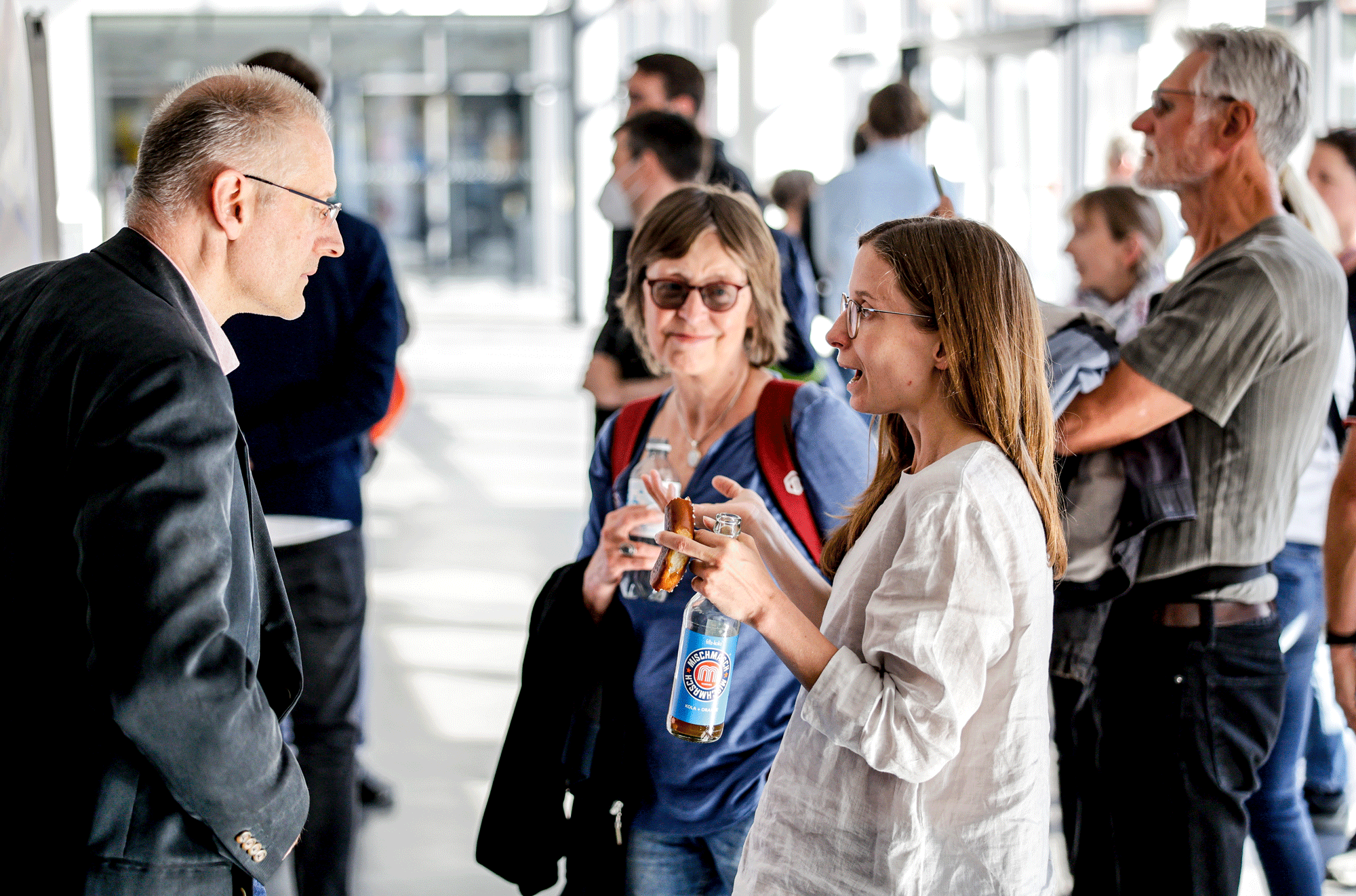 Drei Personen unterhalten sich in einem Foyer miteinander.