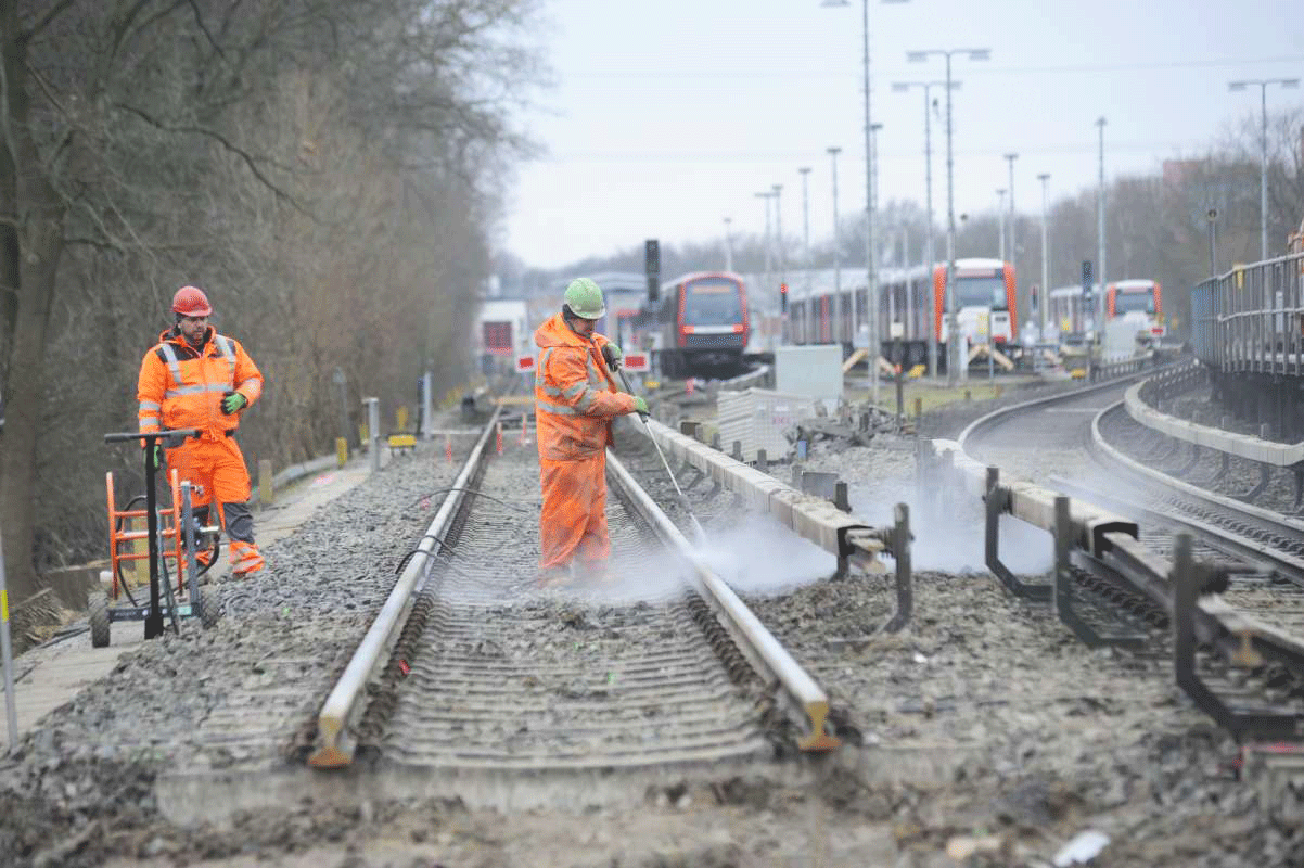 Arbeiter in Warnwesten führen Gleisbauarbeiten durch.