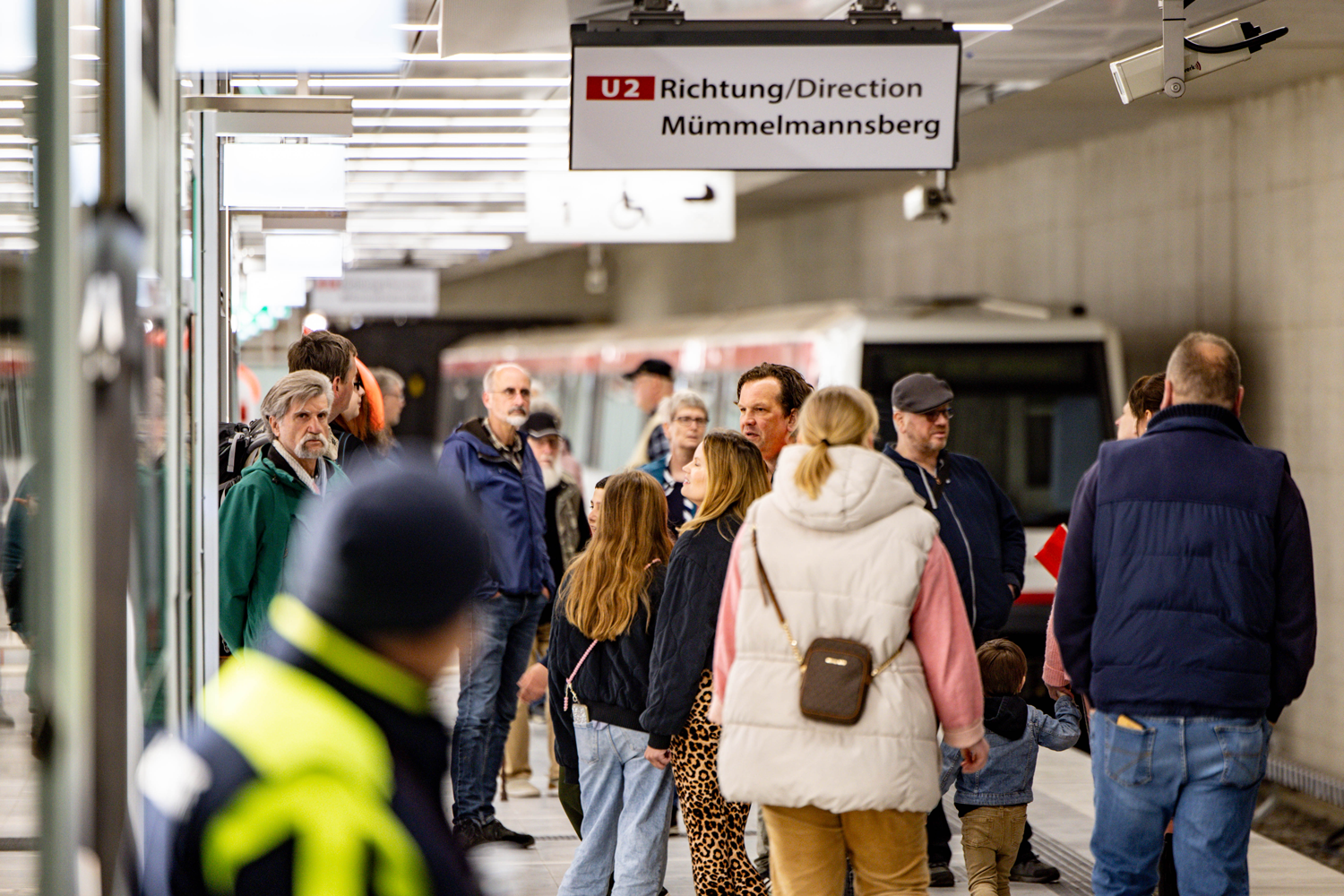 Gewusel auf dem Bahnsteig Horner Rennbahn. Menschen schauen sich um, im Hintergrund verschwommen stehender U-Bahn-Wagon.