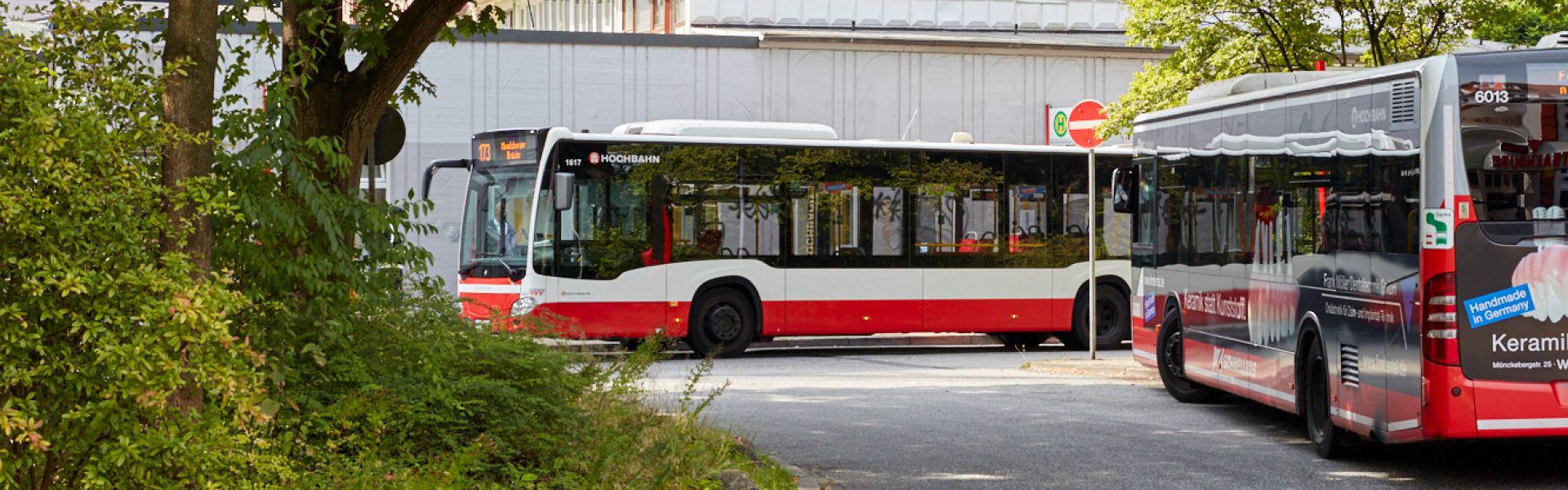 Einfahrt mit zwei Bussen. Einer steht, der andere fährt gerade um die Kurve.