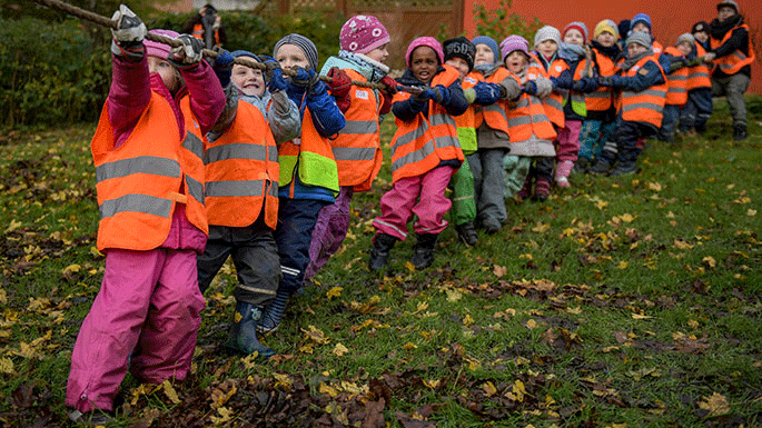 Eine Gruppe von Kindern in Warnwesten zieht gemeinsam an einem Seil.