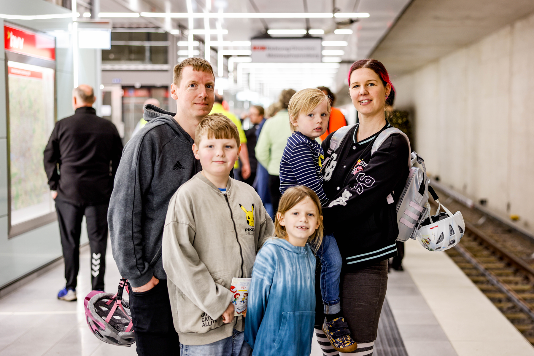 Familie steht auf dem neuen Bahnsteig der Haltestelle Horner Rennbahn und schaut in die Kamera. 