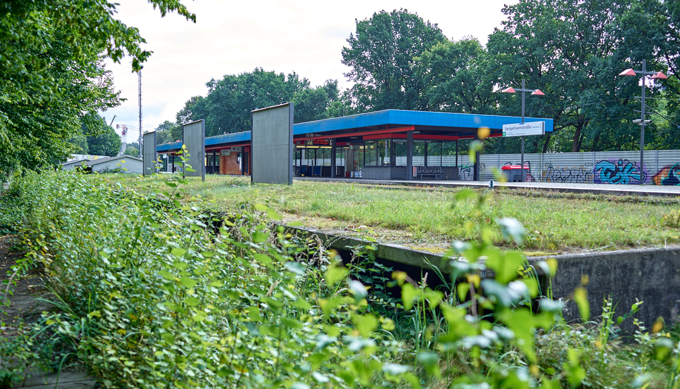 Zu sehen ist die U-Bahn-Haltestelle Sengelmannstraße vor dem Umbau von außen. Im Fokus des Bildes der alte ungenutzte Bahnsteig. 