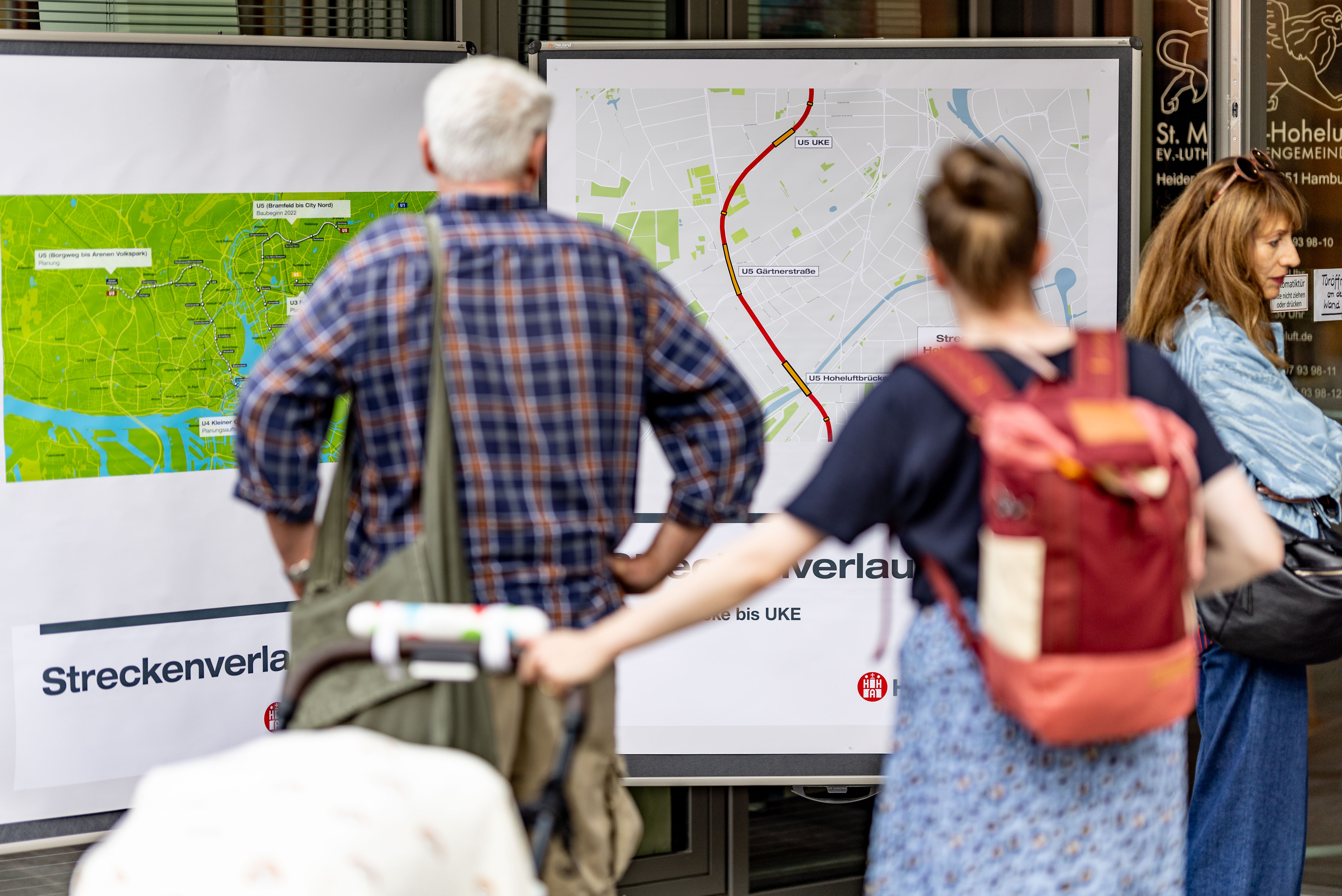 Zwei Personen schauen auf die Infostände zum Streckenverlauf. 