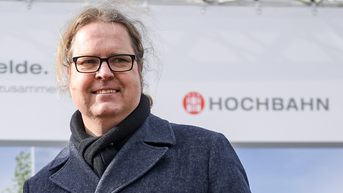 HOCHBAHN-Projektleiter Volker Schmidt vor einem Banner der HOCHBAHN