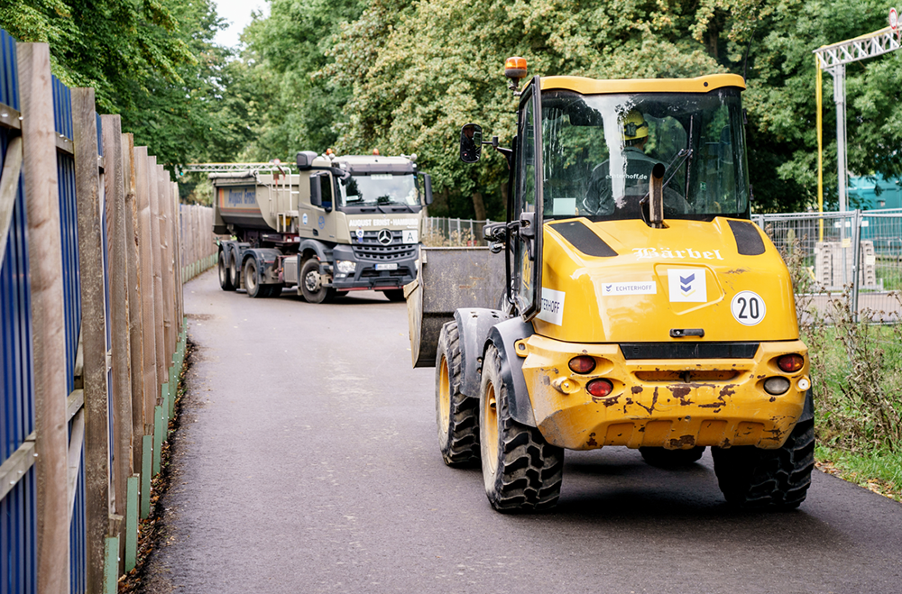 Ein Bagger und ein Laster fahren auf der Baustraße 