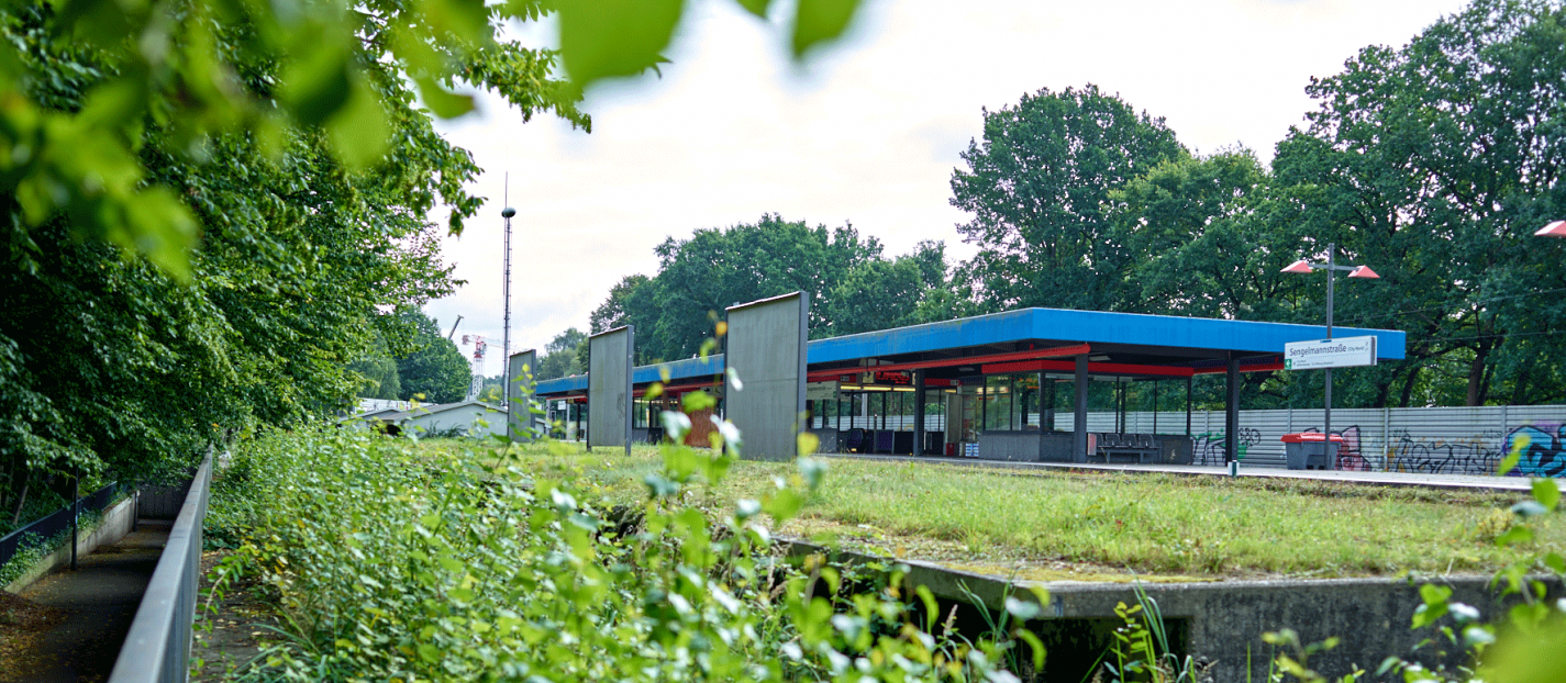 Zu sehen ist die U-Bahn-Haltestelle Sengelmannstraße vor dem Umbau von außen. Im Fokus des Bildes der alte ungenutzte Bahnsteig. 