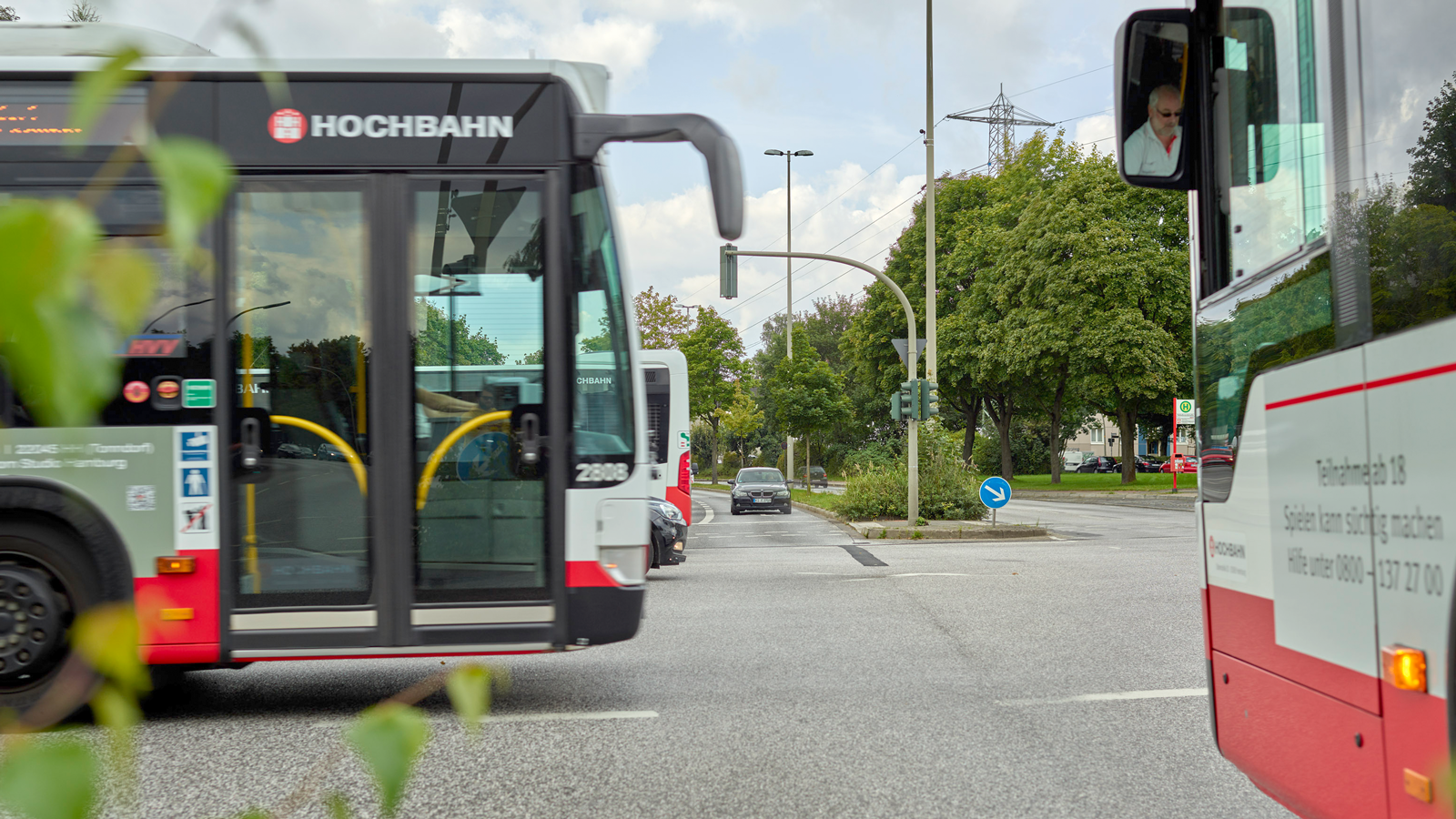 Busse kreuzen sich auf einer Straße. Im Fokus die rechte Seite eines Busses. 