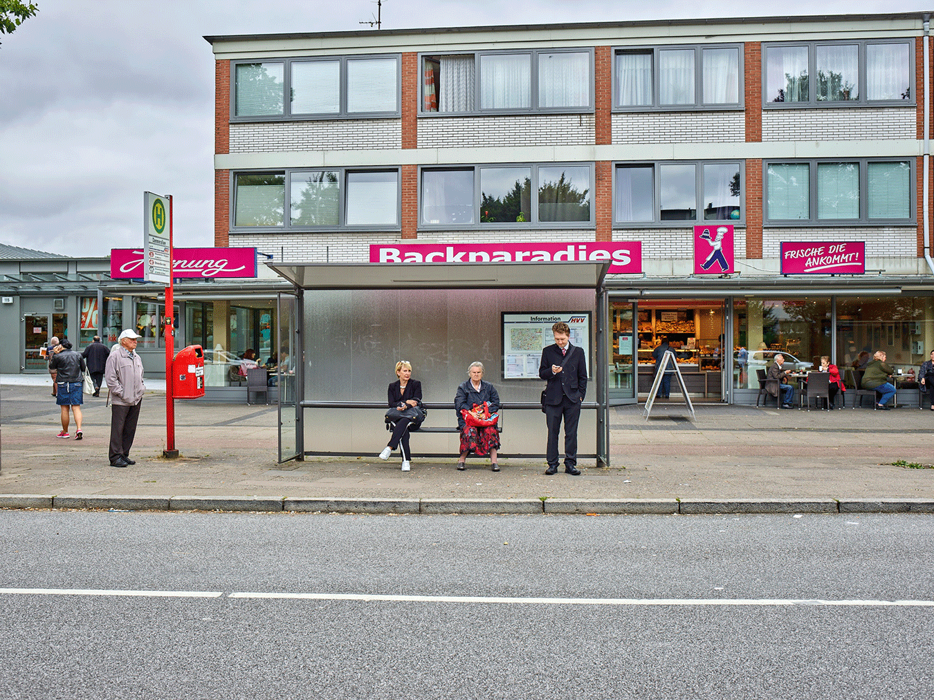 Menschen stehen an der Bushaltestelle Dannerallee und warten.