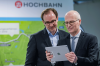 HOCHBAHN-Chef Henrik Falk (l.) und Hamburgs Erster Bürgermeister Dr. Peter Tschentscher schauen auf ein Tablet.