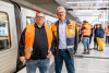 Projektleiter Niels Schefe und Dirk Göhring mit orangenen Westen vor Zug am Bahnsteig Horner Rennbahn.